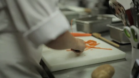 Chef peels carrots in a kitchen Stock Footage 90886213