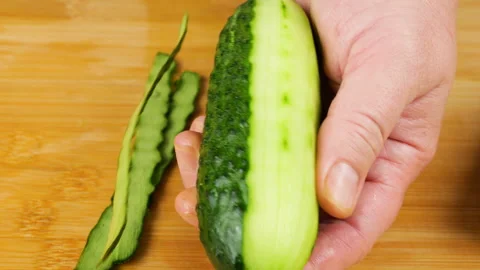 A chef peels a green cucumber with a white plastic vegetable peeler.  库存影片 341542255