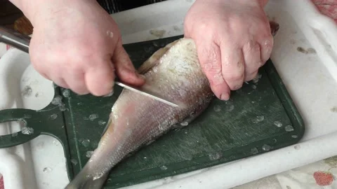 The chef peels raw fish with a knife Stock Footage 166334062