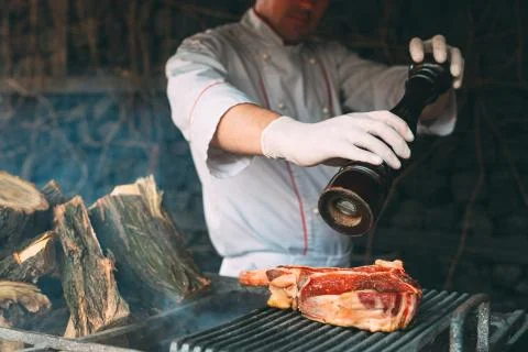 Chef pepper the steak on the fire. Stock Photos