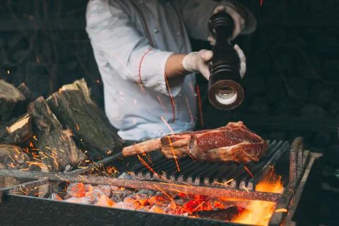 Chef pepper the steak on a fire. Stock Photos