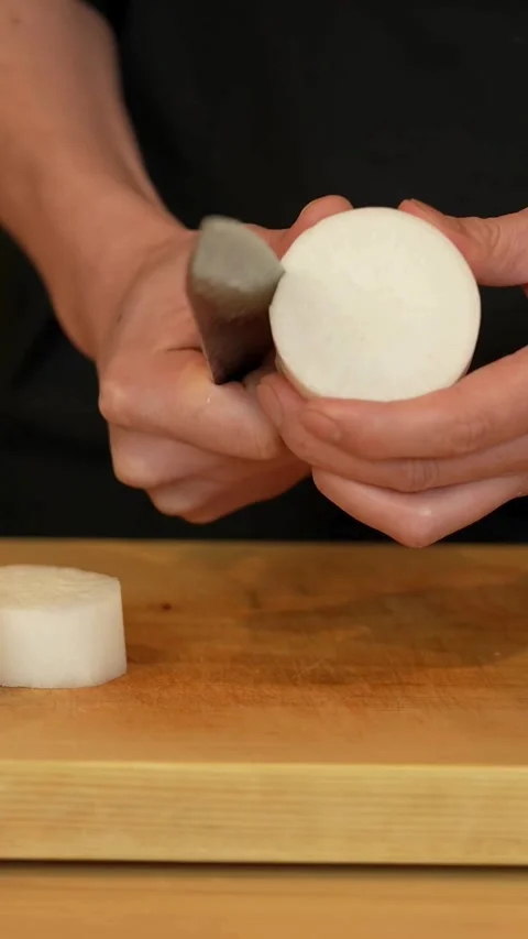 Chef performs katsuramuki technique on thick white daikon radish Stock Footage 331770427