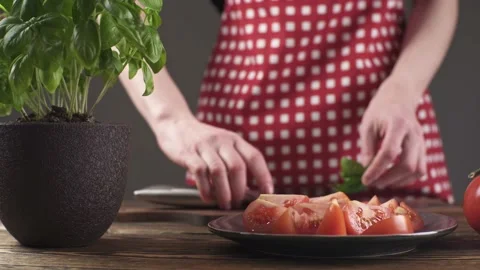 Chef is picking basil leaves, cutting them and sprinkling tomatoes with them Stock Footage 196228378