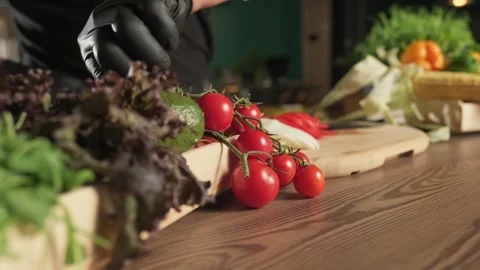 Chef picking bunch of tomatoes from a basket of herbs with a gloved hand Stock Footage 307763408