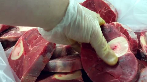 Chef is picking up raw osso buco meat from a box full of fresh veal meat Stock Footage 65125660