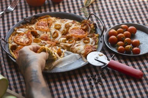 Chef picking up slice of freshly made tomato and onion pizza Stock Photos
