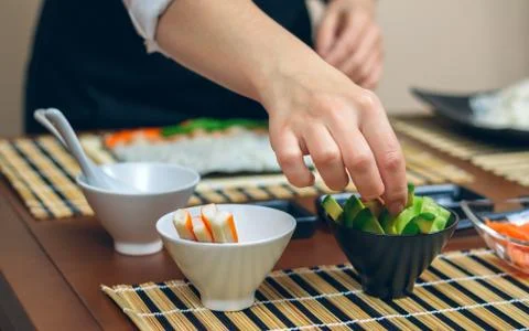 Chef picking up sliced avocado to make sushi Stock Photos