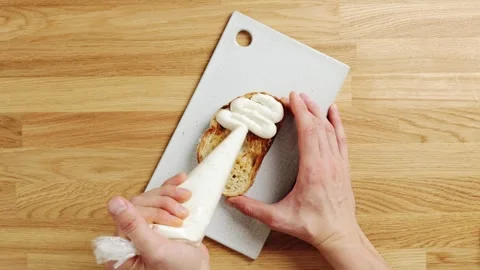 Chef pipes whipped ricotta onto toasted bread. Video stock 344769748