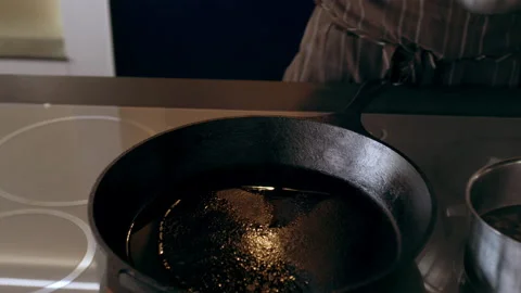 Chef places pieces of sliced shallots into a hot pan in interior kitchen with so Video stock 199455384
