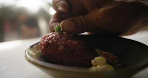 Chef places a small garnish of a green bud on top of the dish of steak tartar Stock Footage 274654850