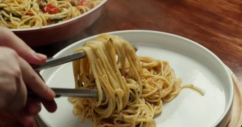 The chef places spaghetti with sliced cherry tomatoes and salmon pieces with Stock Footage 317722824