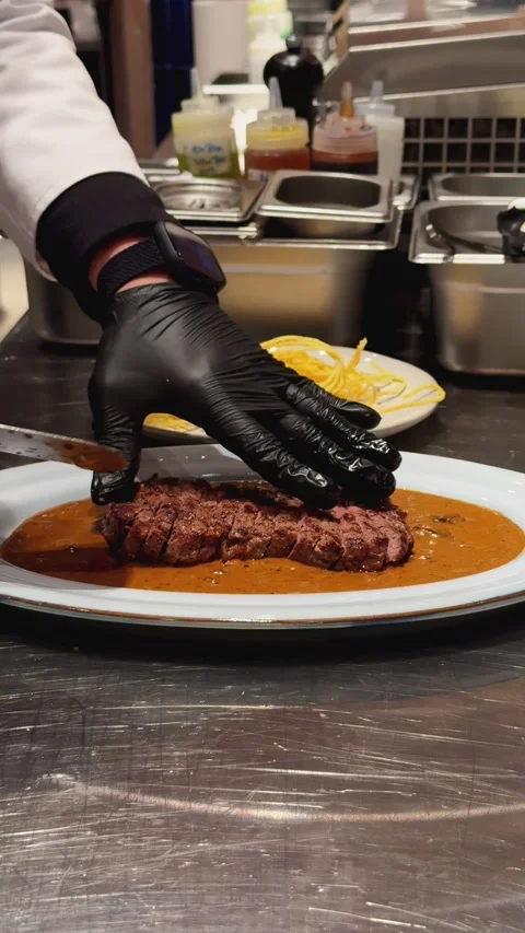 Chef placing and presenting a sliced medium-rare beef steak on a plate Stock Footage 337462122