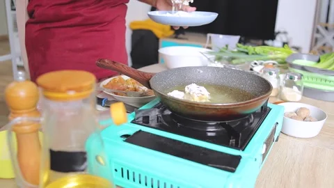 Chef placing battered tuna pieces into hot frying pan with oil on portable stove Stockbeeldmateriaal 341487594