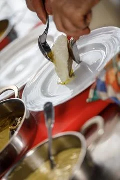 A chef is placing a cod in a plate Stock Photos