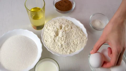 Chef placing eggs near flour, sugar, milk, oil, and cinnamon for baking. Stock Footage 311526218
