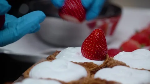 Chef placing fresh strawberry on cream-filled puff pastry dessert close-up Stock Footage 343018676