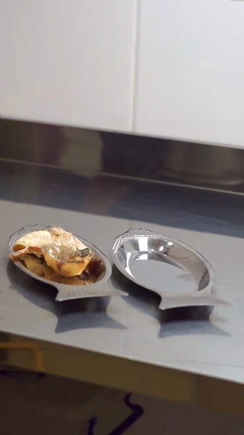 Chef placing freshly fried fish pieces onto fish-shaped metal plates using tongs Stock Footage 342345258