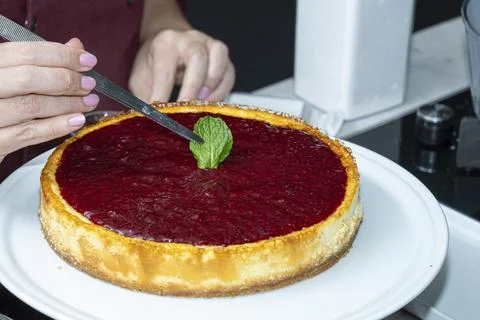 Chef placing a mint leaf on cheesecake with berry topping. Stock Photos