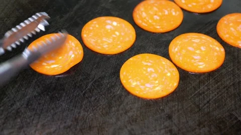 Chef placing pepperoni slices on a hot flat top grill in commercial kitchen Stock Footage 324711117