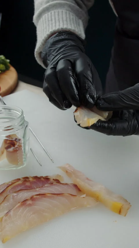 Chef placing smoked fish slice into glass jar Stock Footage 308353584