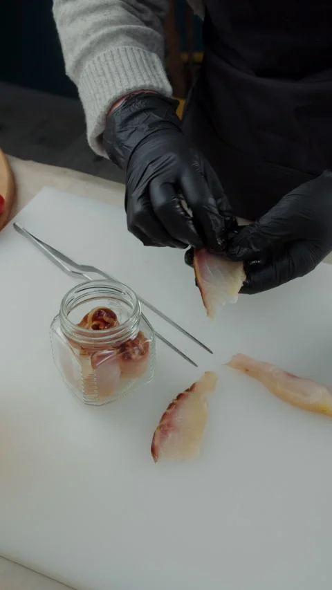 Chef placing smoked fish slice into glass jar Video stock 308353935