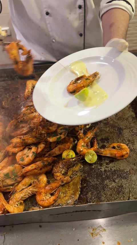 A chef plates grilled shrimp in a buffet dining area, carefully arranging the 스톡 동영상 282801050