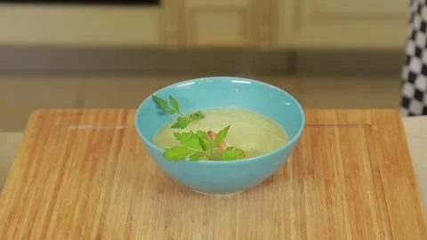 A chef plating and presenting broccoli cream soup with shrimp and fresh herbs Stock Footage 340553917