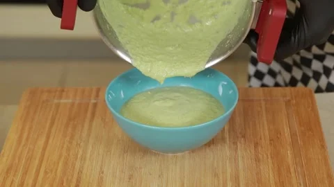 A chef plating and presenting broccoli cream soup with shrimp and fresh herbs Stock Footage 340553919