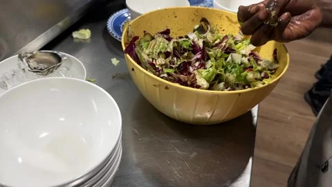 Chef plating fresh vegetable salad with lettuce, tomatoes and mixed greens into Stock Footage 348035198