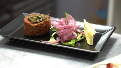 Chef plating a gourmet beef steak tartare with capers and pickled onions Stock Footage 337900728