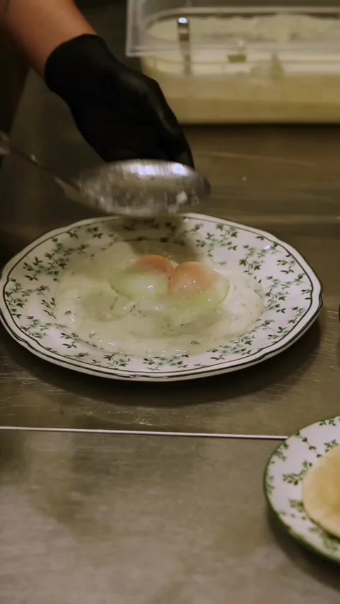 Chef plating poached eggs for Turkish eggs breakfast dish in a cafe Stock Footage 341578699