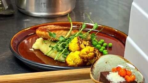 Chef plating salmon fillet mashed potato pouring sauce restaurant kitchen Stock Footage 341537624