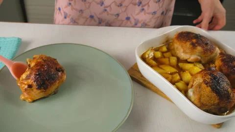 Chef plating serving roasted chicken thighs and potatoes from baking dish. Stock Footage 317174694