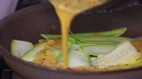 Chef Pouring Beaten Egg Mixture Over Fresh Zucchini Slices in a Frying Pan Stock-Footage 339629399