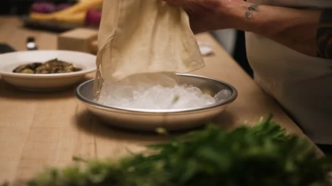 Chef pouring crushed ice into silver bowl for oysters during kitchen prep Stock Footage 169227416