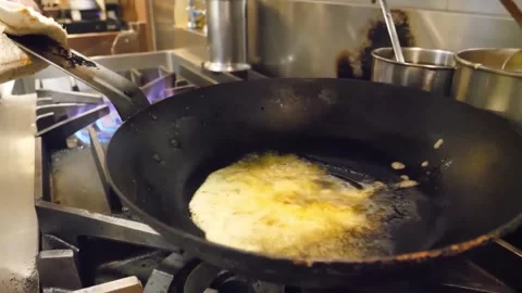 Chef Pouring Egg Batter into Hot Wok on Commercial Gas Stove Stock-Footage 347687991