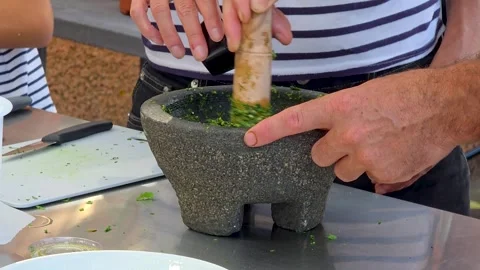 Chef pouring extra virgin olive oil while crushing fresh basil and herbs in  Stock Footage 348027415