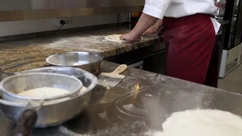 The chef pouring grated cheese on the dough with tomato sauce in a pizzeria. Stock Footage 308000796