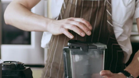 Chef pouring ground herbs from a blender into a bowl in interior kitchen with so Stock Footage 199459783