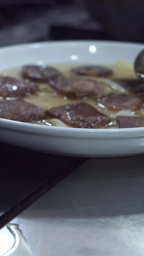 Chef pouring hot meat broth with a ladle over dough sheets and sliced beef for t Stock Footage 341352417