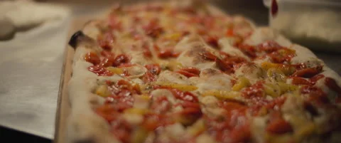 Chef pouring a hot sauce over a cherry tomato al taglio pizza. Slow motion. Stock Footage 147518315