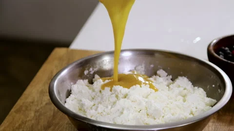 Chef pouring mixture of the egg yolks and butter into a bowl with curd cheese 4K Stock Footage 135445606
