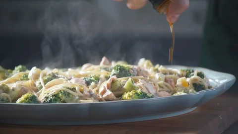 Chef is pouring sauce ready spaghetti pasta on a plate in a restaurant kitchen. Vidéo 124711100