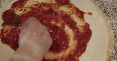 Chef pouring tomato paste on round raw pizza dough Stock Footage 221634958