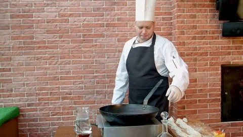 Chef pouring vegetable oil to the pan, talking to a camera Stockbeeldmateriaal 74938829