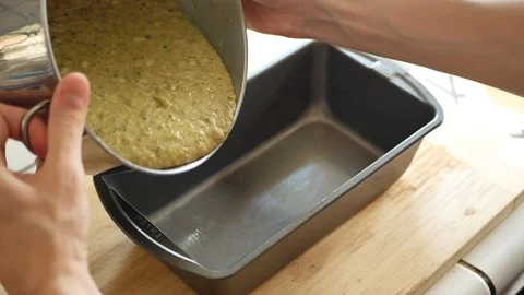 Chef pouring zucchini bread batter into loaf pan while baking in kitchen. Stock Footage 92661814