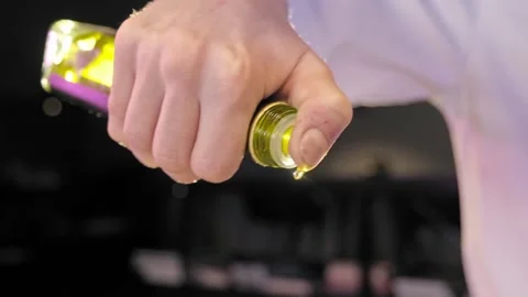 Chef pours abundantly one hand yellow olive oil from glass bottle  Stock Footage 170232965