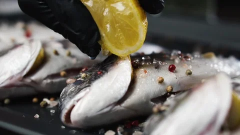 Chef pours fresh fish with lemon juice, slow motion. Healthy eating concept. Stock Footage 125249569