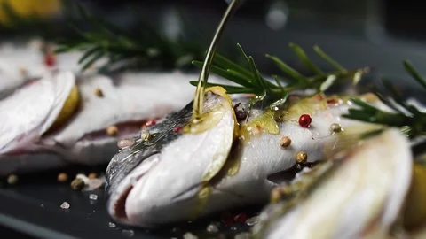 Chef pours fresh fish with olive oil, slow motion. Healthy eating concept. Video stock 125249514