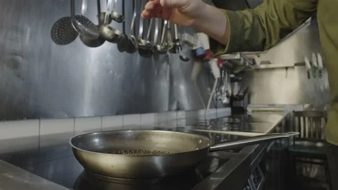 The chef pours pepper into the pan and begins to masterfully mix it. Stock Footage 234921372